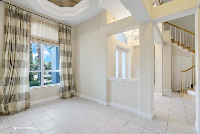 spare room with a tray ceiling and light tile patterned floors