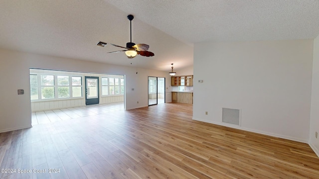 unfurnished living room featuring ceiling fan, a textured ceiling, light wood-type flooring, and lofted ceiling