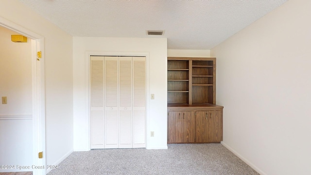 unfurnished bedroom with light carpet, a textured ceiling, and a closet