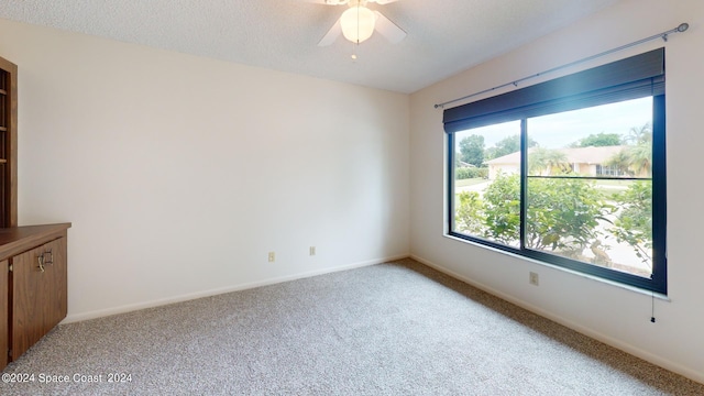 empty room featuring baseboards, light carpet, a textured ceiling, and ceiling fan