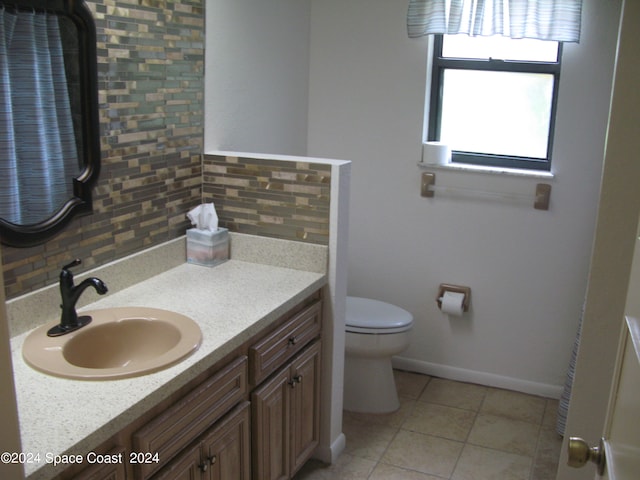 bathroom with tile patterned flooring, backsplash, vanity, and toilet