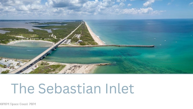 birds eye view of property with a water view and a beach view