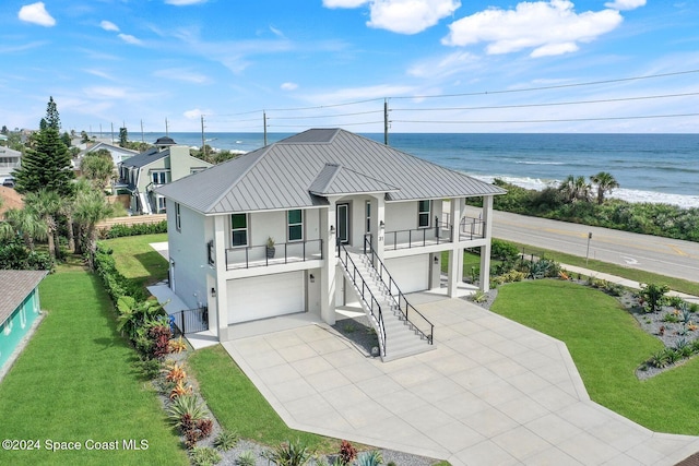 view of front of property with a garage, a front lawn, and a water view