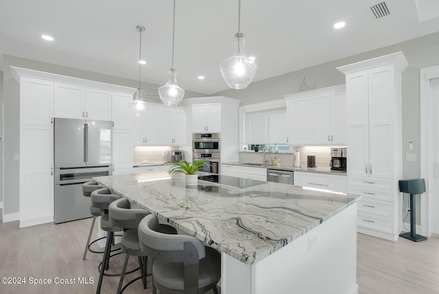 kitchen featuring decorative backsplash, light hardwood / wood-style flooring, stainless steel appliances, a large island, and white cabinets