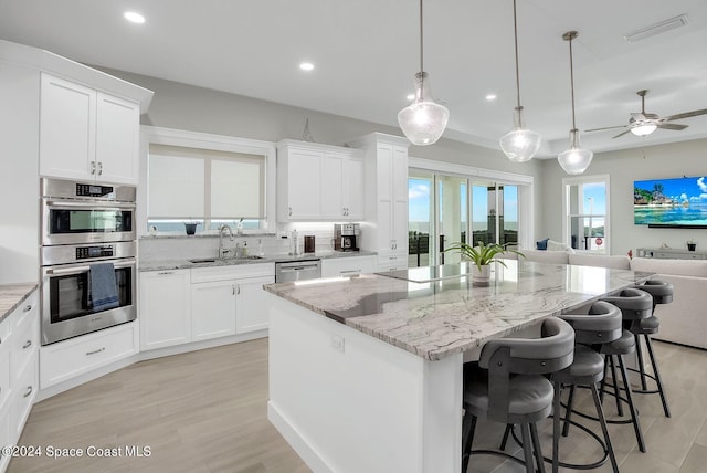 31 Seabridge Dr, Ormond Beach, FL 32176 - kitchen featuring appliances with stainless steel finishes, open floor plan, light wood-style floors, recessed lighting, and light stone countertops