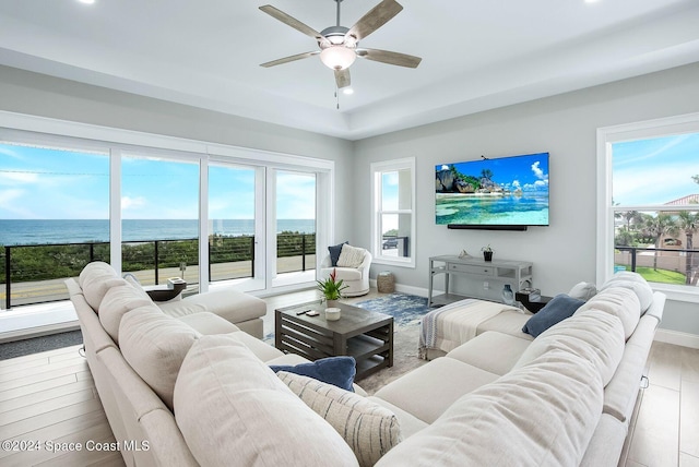 living room with a water view, light hardwood / wood-style floors, a healthy amount of sunlight, and ceiling fan