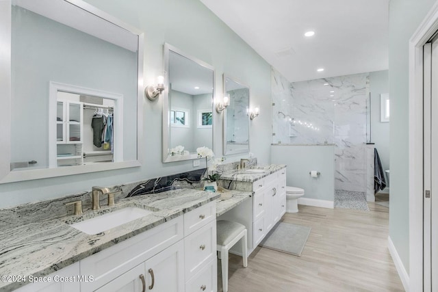 bathroom with vanity, tiled shower, hardwood / wood-style floors, and toilet