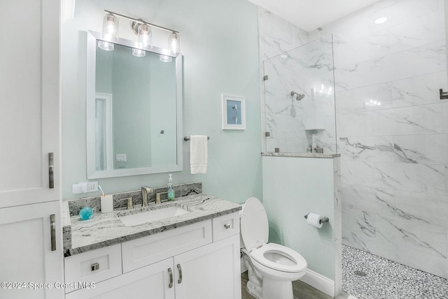 bathroom with a tile shower, toilet, and vanity