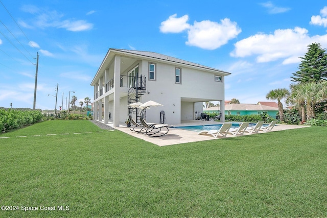 rear view of house with a patio, a balcony, and a lawn