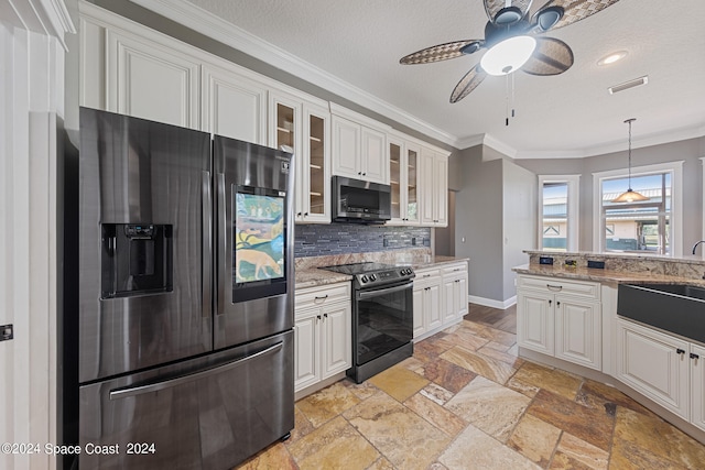 kitchen with light stone counters, white cabinets, stainless steel appliances, ornamental molding, and ceiling fan