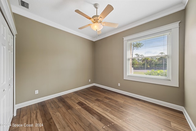 unfurnished bedroom featuring wood-type flooring, a closet, crown molding, and ceiling fan