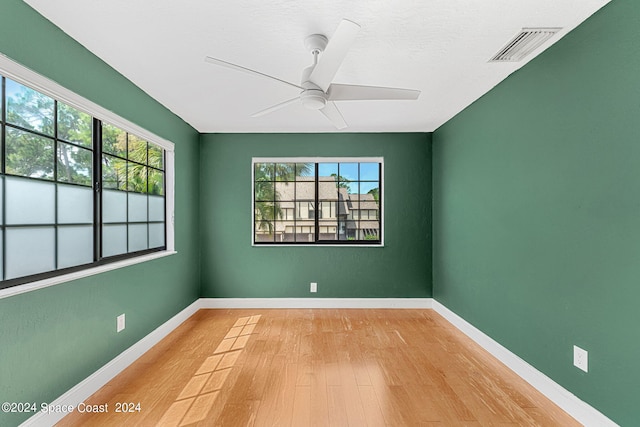 empty room featuring ceiling fan, light hardwood / wood-style floors, and a wealth of natural light