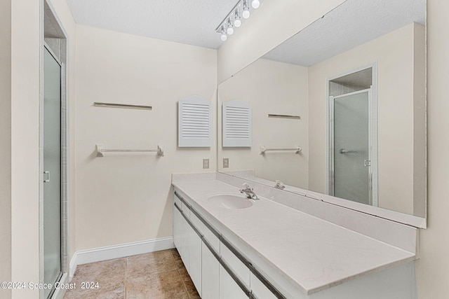 bathroom featuring vanity, a shower with shower door, a textured ceiling, and tile patterned floors