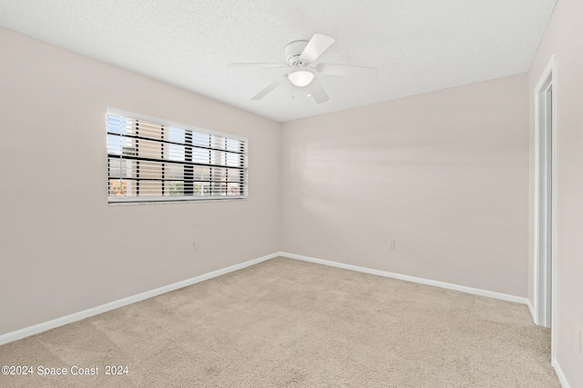 spare room with a textured ceiling, carpet flooring, and ceiling fan