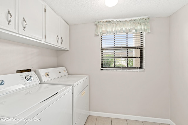 washroom featuring cabinets, a textured ceiling, light tile patterned floors, and washer and clothes dryer