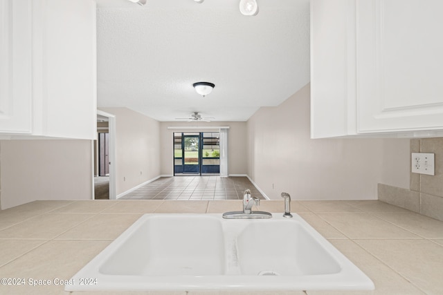 kitchen featuring light tile patterned flooring, sink, ceiling fan, and white cabinets