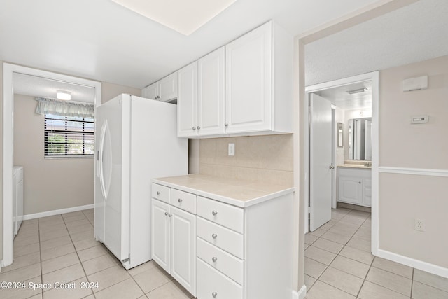 kitchen with washing machine and clothes dryer, light tile patterned floors, white cabinetry, and white refrigerator with ice dispenser