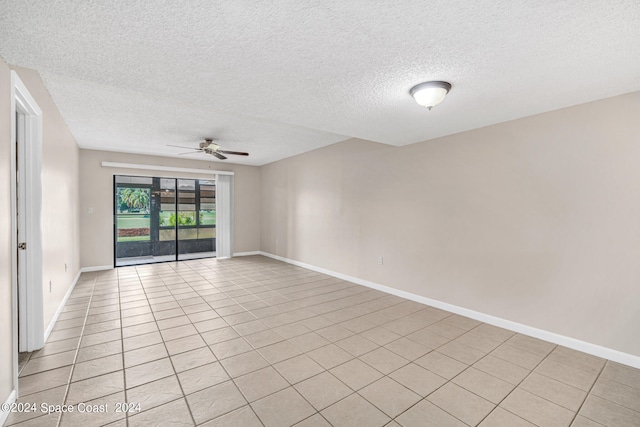 empty room with ceiling fan, light tile patterned flooring, and a textured ceiling