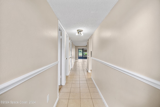 corridor with a textured ceiling and light tile patterned floors