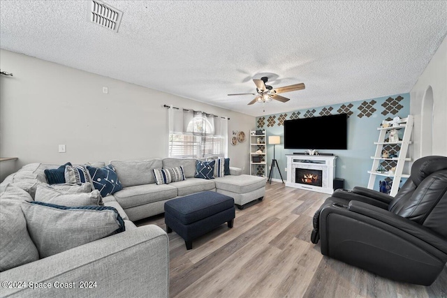 living room with a textured ceiling, hardwood / wood-style floors, and ceiling fan