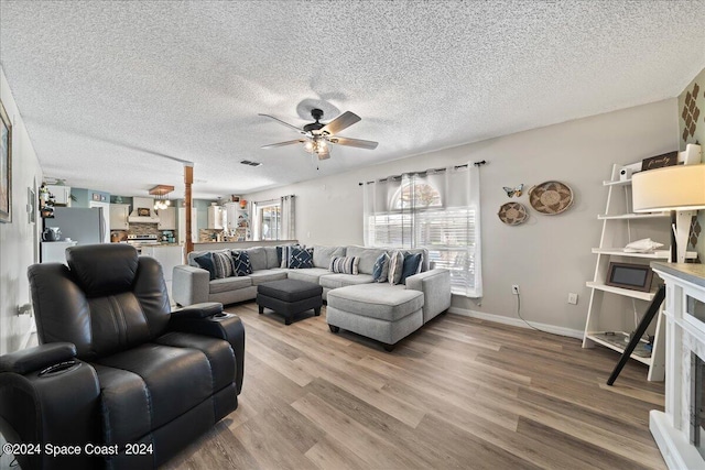 living room featuring ceiling fan, a textured ceiling, and hardwood / wood-style floors