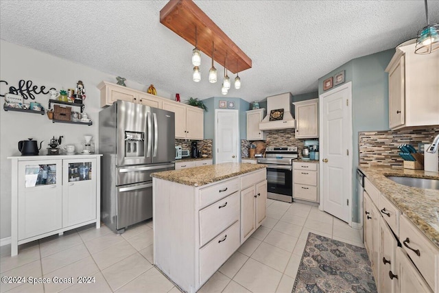 kitchen with pendant lighting, a textured ceiling, sink, a kitchen island, and appliances with stainless steel finishes