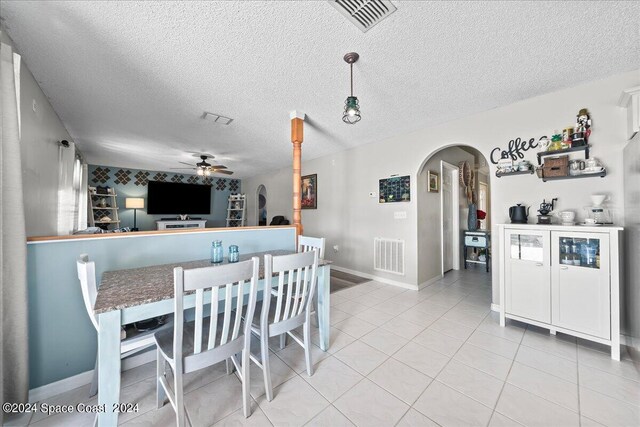 dining area with a textured ceiling, light tile patterned flooring, and ceiling fan