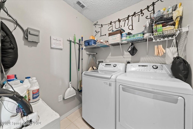 laundry area with a textured ceiling, washer and clothes dryer, and light tile patterned floors