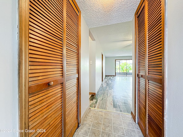 hallway with a textured ceiling and hardwood / wood-style floors