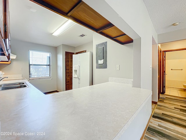 kitchen with a textured ceiling, white fridge with ice dispenser, sink, and hardwood / wood-style flooring