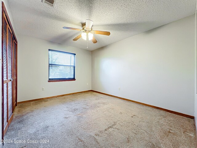 spare room with a textured ceiling, carpet flooring, and ceiling fan