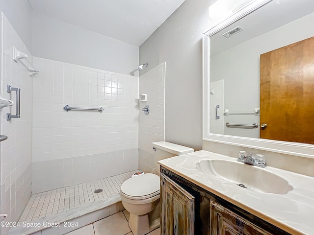 bathroom featuring vanity, tile patterned floors, toilet, and tiled shower