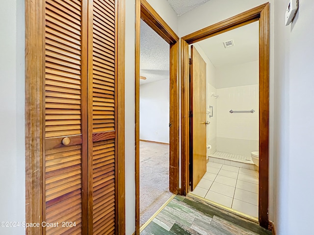 hall with a textured ceiling and light hardwood / wood-style floors