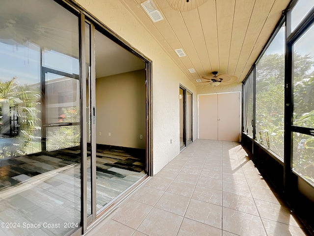 unfurnished sunroom featuring wooden ceiling, ceiling fan, and plenty of natural light