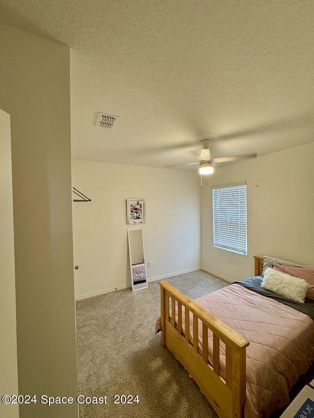 bedroom featuring ceiling fan, carpet floors, and a textured ceiling