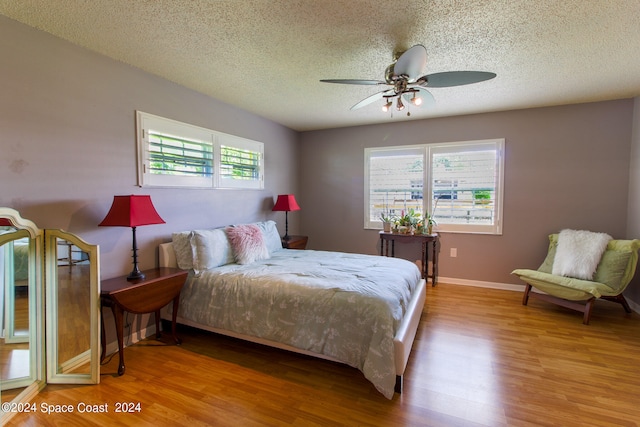 bedroom with ceiling fan, a textured ceiling, and light hardwood / wood-style floors