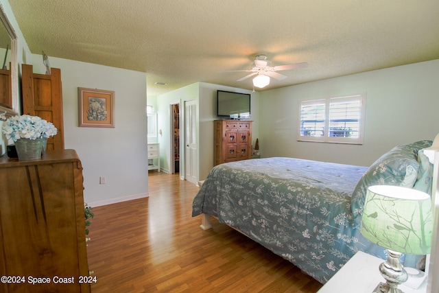 bedroom with connected bathroom, ceiling fan, hardwood / wood-style floors, and a textured ceiling