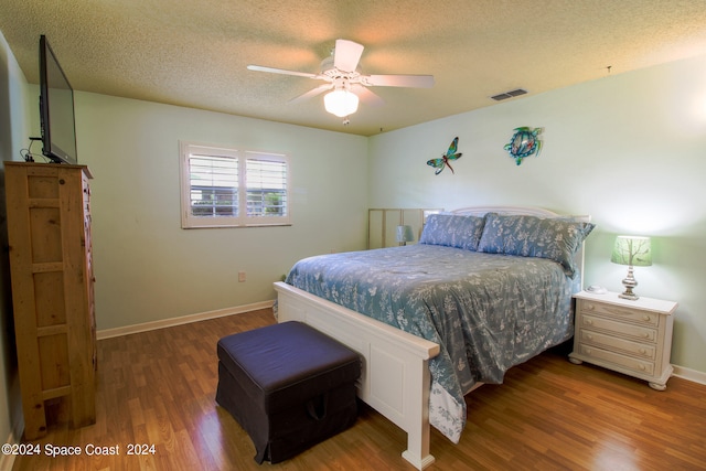 bedroom featuring ceiling fan, a textured ceiling, and dark hardwood / wood-style flooring