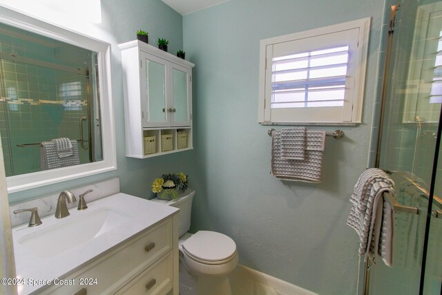 bathroom featuring vanity, toilet, and a shower with shower door