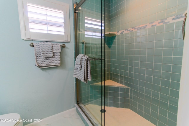 bathroom with a shower with shower door and toilet