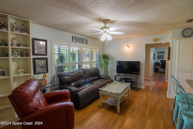 living room with a textured ceiling, ceiling fan, and light hardwood / wood-style flooring