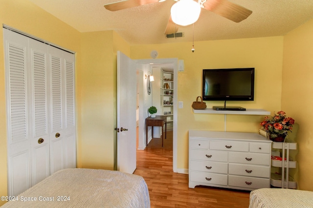 bedroom with a textured ceiling, light hardwood / wood-style floors, ceiling fan, and a closet