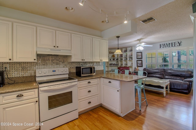 kitchen featuring kitchen peninsula, light wood-type flooring, a kitchen bar, ceiling fan, and electric range