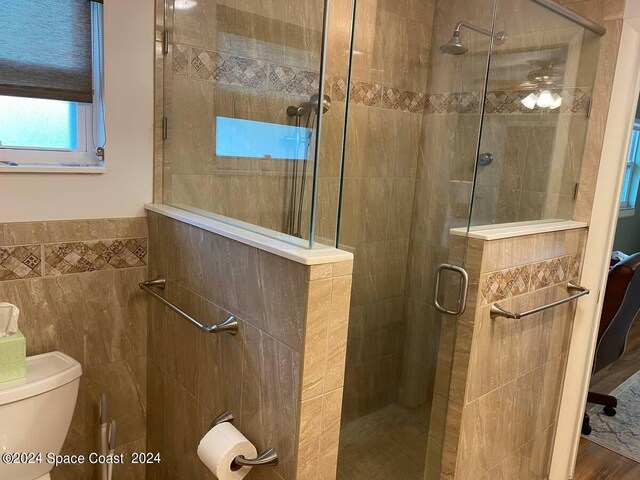 bathroom with walk in shower, hardwood / wood-style floors, toilet, and ceiling fan