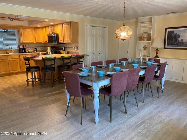 dining room with light hardwood / wood-style flooring, a textured ceiling, sink, and crown molding