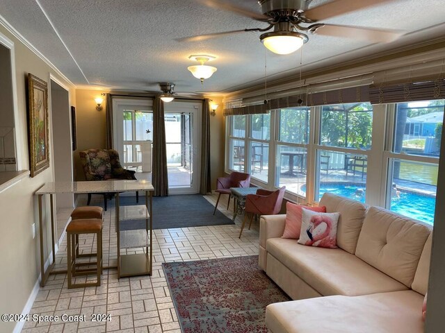 living room featuring a textured ceiling, ornamental molding, and ceiling fan