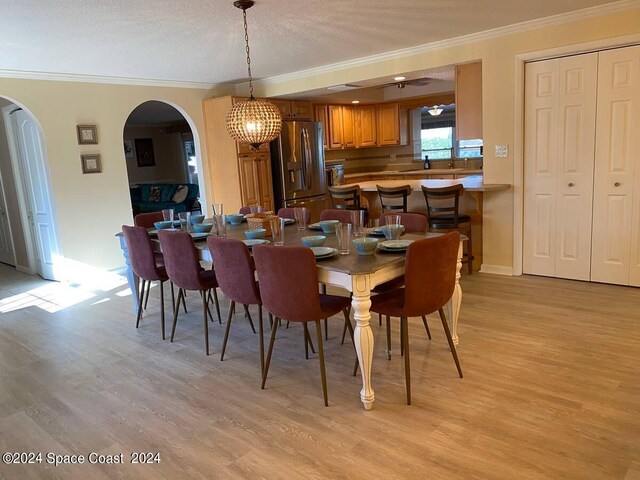 dining room featuring a textured ceiling, ceiling fan with notable chandelier, ornamental molding, and light hardwood / wood-style flooring