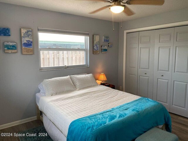 bedroom featuring a textured ceiling, dark hardwood / wood-style flooring, ceiling fan, and a closet