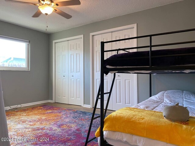 bedroom featuring a textured ceiling, two closets, ceiling fan, and hardwood / wood-style flooring