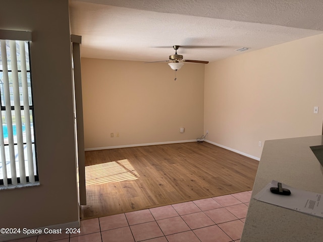 spare room featuring a textured ceiling, ceiling fan, and light hardwood / wood-style flooring